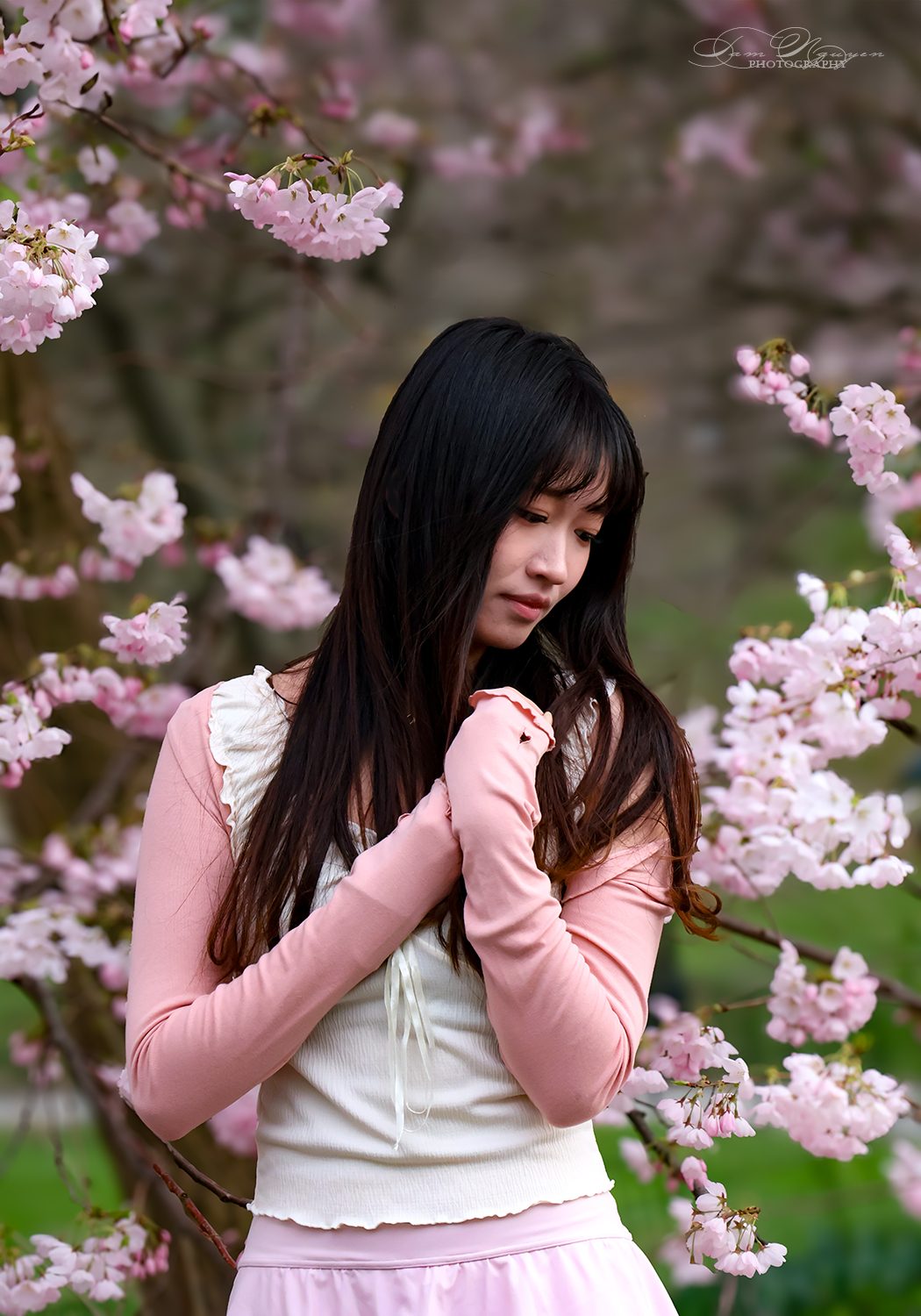 A young woman among cherry blossom branches.